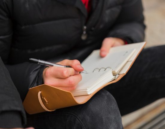 close-up-guy-writing-notebook